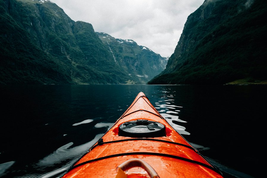 Proa de un kayak avanzando por un lago rodeado de montañas