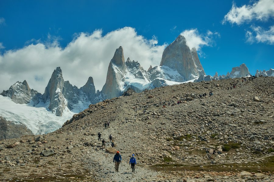 Caminantes en un sendero de trekking con picos nevados de fondo